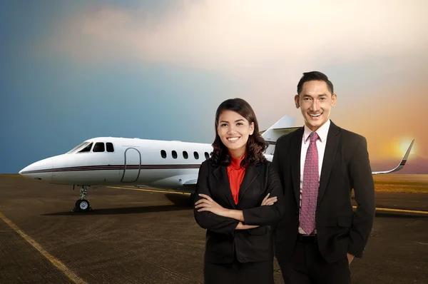 Homme d'affaires et femme souriant devant un jet privé — Photo