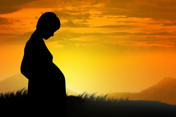 Silhouette de la femme enceinte au coucher du soleil — Photo