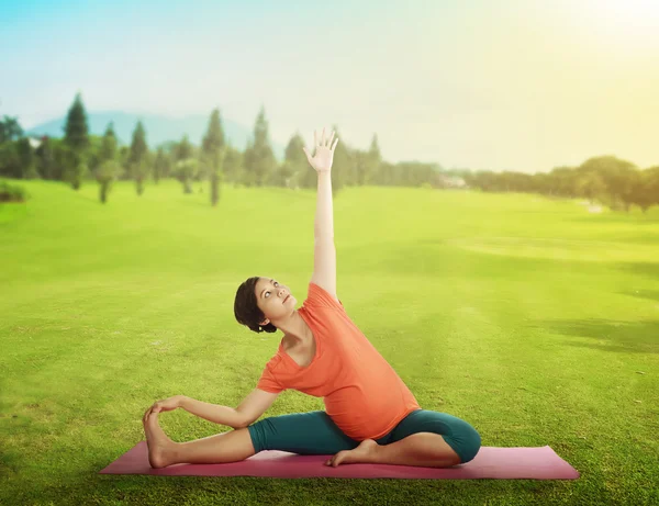 Zwangere moeder doet yoga op het gras — Stockfoto