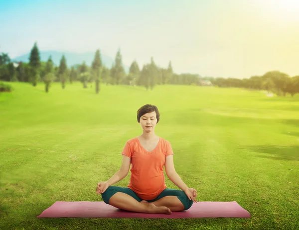 Gravida mamma gör yoga på gräset — Stockfoto