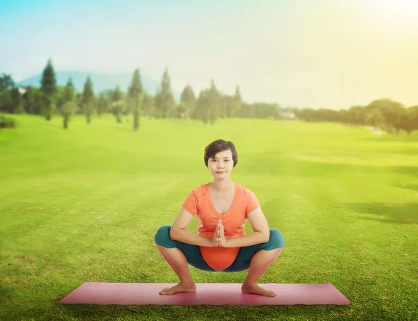 W ciąży matka robi joga na trawie — Zdjęcie stockowe