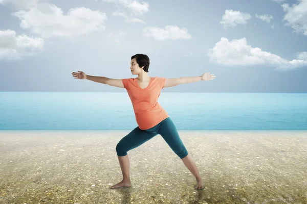 Pregnant mother doing yoga at the beach — Stock Photo, Image