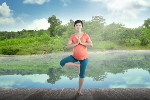 Gravida mamma gör yoga vid sjön — Stockfoto