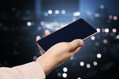 Cep telefonu ile boş ekran bulanık gece şehir üzerinde tutan el
