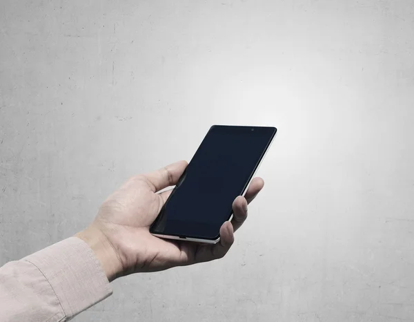 Hand som håller cellphone med blank skärm på grunge bakgrund — Stockfoto