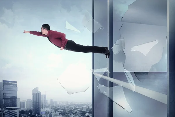 Affärsman som flyger genom kontorsbyggnad fönster — Stockfoto