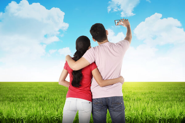 Пара, делающая селфи посреди луга
