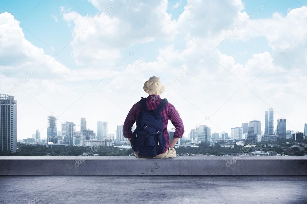 A traveler sitting on the rooftop watching at the city