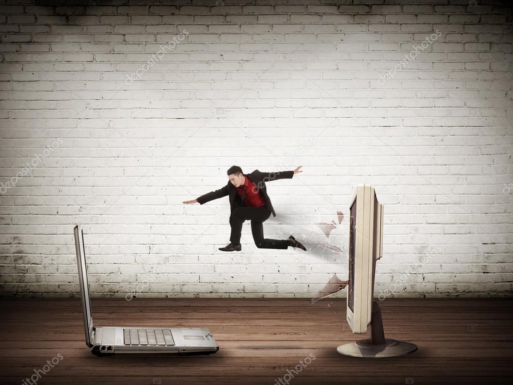 Business man jumping from desktop computer to laptop