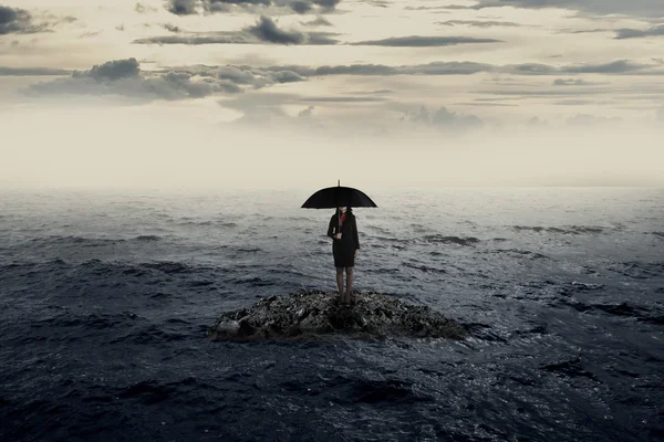 Donna con ombrello sulla roccia in mezzo al mare — Foto Stock