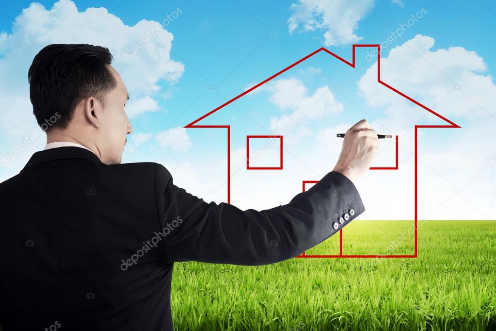 Business man drawing house on the meadow