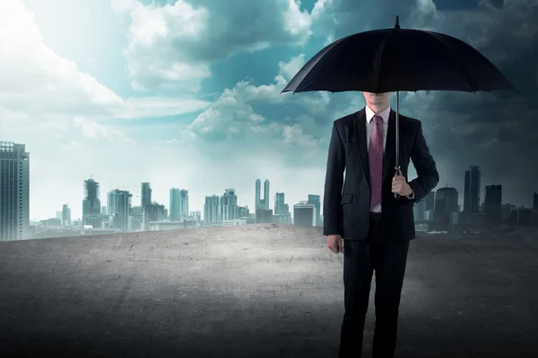 Business man holding umbrella on the rooftop — Stock Photo, Image