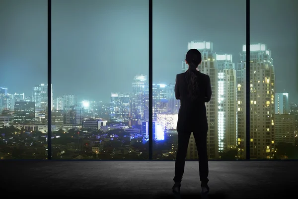 Femme debout dans son bureau regardant la ville — Photo