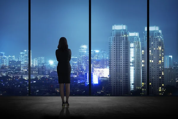 Femme debout dans son bureau regardant la ville — Photo