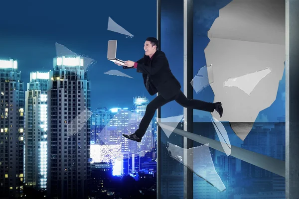 Homem com laptop saltar através da janela do escritório — Fotografia de Stock
