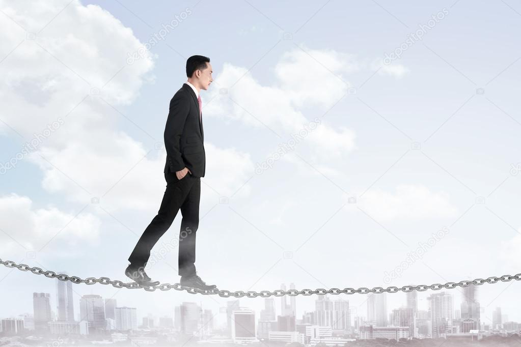 Business man walking on the chain