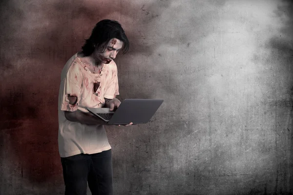 Scary male zombie typing with laptop — Stock Photo, Image