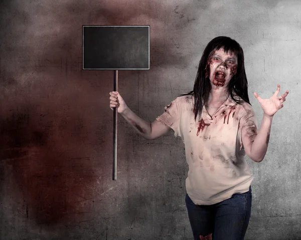 Creepy female zombie holding wooden board — Stock Photo, Image