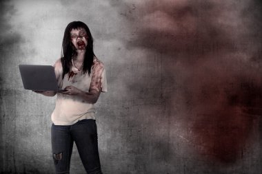 Kadın zombi dizüstü grunge arka plan üzerinde tutan