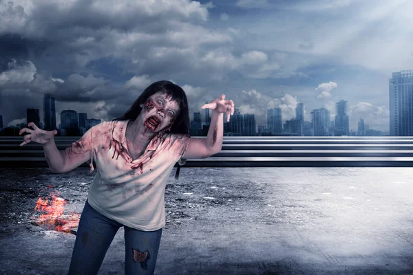 Skrämmande kvinnliga zombie med brinnande staden bakgrund — Stockfoto