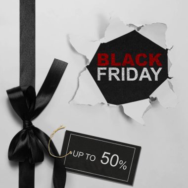 Etiketinde% 50 'ye kadar metin olan beyaz yırtık kağıt ve Kara Cuma metninin üst görüntüsü. Uzayı kopyala Düz yatıyordu. Kara Cuma satış konsepti