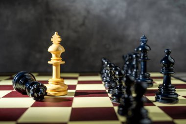 Satranç tahtasındaki zıt taşlara karşı duran beyaz bir satranç kralının yakın görüntüsü. Strateji kavramı