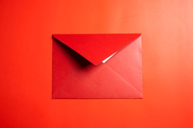 Kırmızı arkaplanda kırmızı zarf ya da kartpostalın üst görüntüsü. Model, boş şablon, kopyalama alanı. Düz yatış biçimine sahip tebrik ya da davet kartı