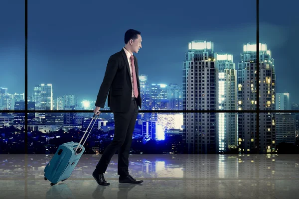 Business man walking with suitcase over city background — Stock Photo, Image