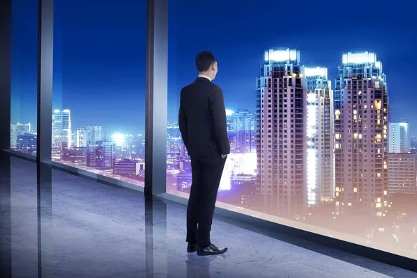 Biznes człowiek patrząc na miasto z jego pomieszczenie biurowe — Zdjęcie stockowe