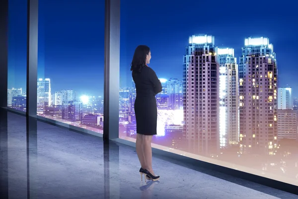 Ділова жінка дивиться місто зі своєї офісної кімнати — стокове фото