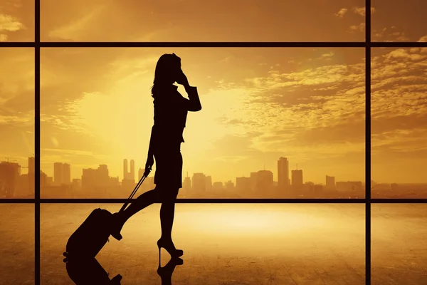 スーツケースと一緒に歩いているビジネス女性のシルエット — ストック写真
