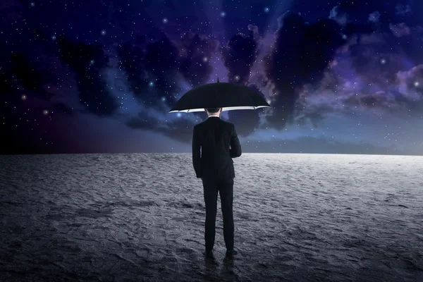 Man holding umbrella from outer space — Stock Photo, Image