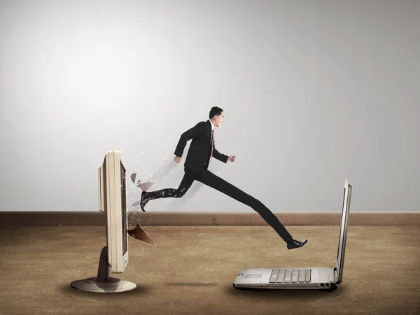 Hombre de negocios con una pierna larga desde el escritorio de la computadora hasta el portátil — Foto de Stock