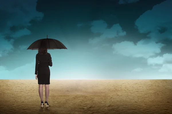 Ділова людина тримає парасольку в пустелі — стокове фото