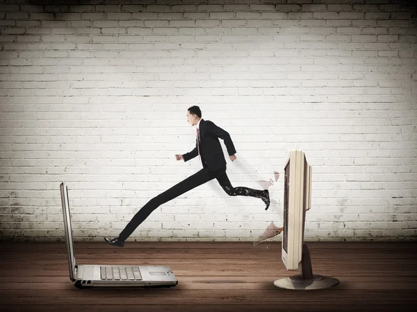 Homem de negócios com perna longa para fora da área de trabalho do computador para laptop — Fotografia de Stock