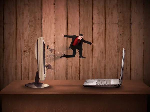 Business man jumping from desktop computer to laptop — Stock Photo, Image