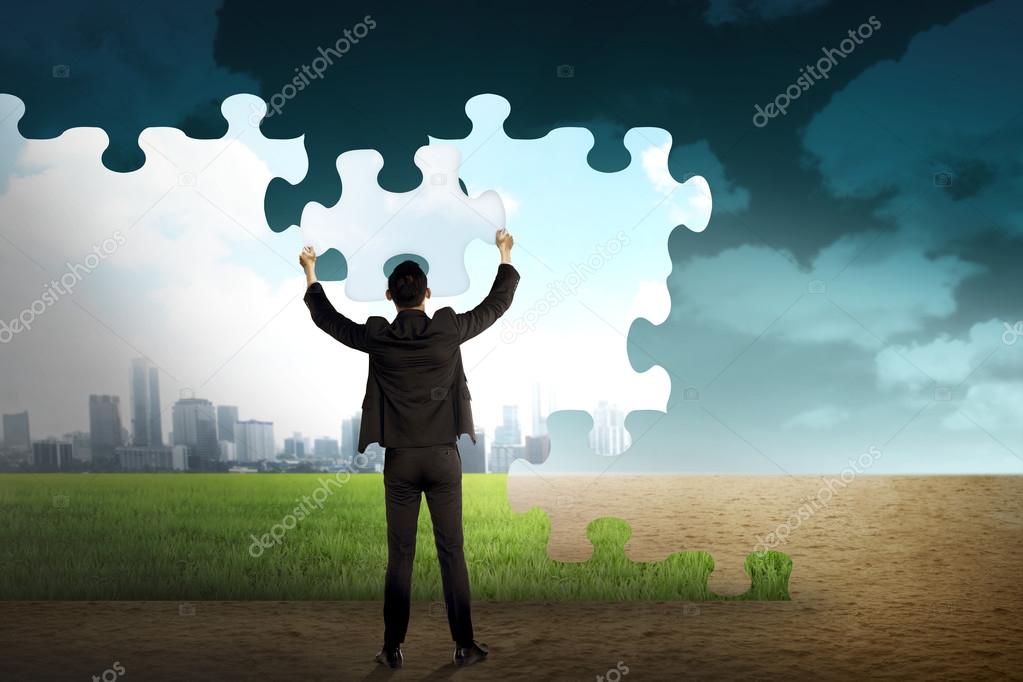 Business person building puzzle of city in the desert