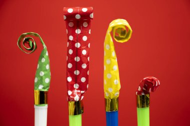 Kırmızı arka planda renkli parti üfleyicileri. Parti ya da bayram kutlaması kavramı