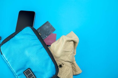 Cep telefonu, kredi kartı, mavi arka planda sırt çantasındaki seyahat şapkası. Model veya Kopyala uzayı. Seyahat, yaz ya da tatil kavramı