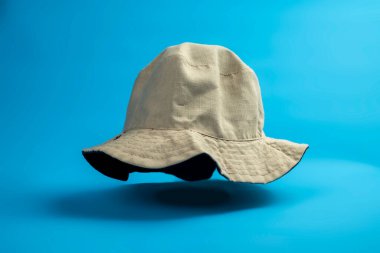 Mavi arka planda bej renkli kova şapka. Seyahat, yaz ya da tatil kavramı