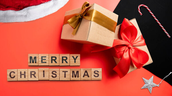 Поздравление с Рождеством смс с подарочной коробкой и конфеткой на красном фоне. Праздничные поздравления или зимние темы. Концепция празднования Рождества