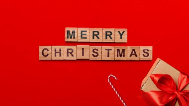 Kırmızı arka planda hediye kutusu ve şeker kamışı olan Mutlu Noeller mesajı. Tatil teması ya da kış teması. Mutlu Noeller kutlaması kavramı
