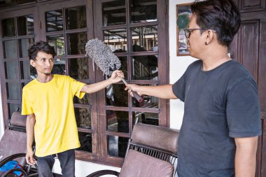 Pencereyi temizlediği için başka bir adama cam sileceği veren bir adam. Günlük rutin işler için evi temizlemek için birlikte çalışıyorlar. Temizlik kavramı