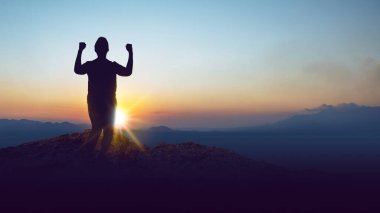 Güneşin doğuşunu kutlamak için kollarını kaldırarak tepenin üstünde duran bir insanın silueti. Kazanan konsepti