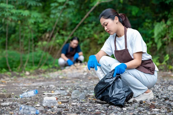 Temizlik sırasında önlük ve eldiven giyen Güneydoğu Asyalılar. Çöplerle dolu çöp torbalarını tutarak. Çöpleri temizleyerek çevreyi korumak.