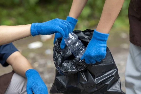 Temizlik sırasında önlük ve eldiven giyen gönüllüler. Çöplerle dolu çöp torbalarını tutarak. Çöpleri temizleyerek çevreyi korumak.