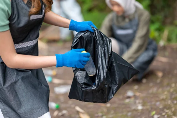 Endonezyalı Güneydoğu Asyalı kadınlar temizlik faaliyetlerinde önlük ve eldiven giyiyorlar. Çöplerle dolu çöp torbalarını tutarak. Çöpleri temizleyerek çevreyi korumak.
