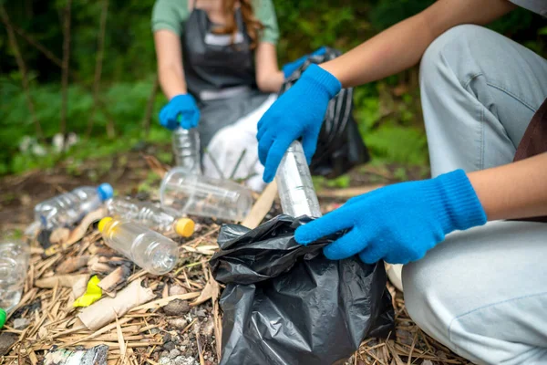Temizlik sırasında önlük ve eldiven giyen gönüllüler. Çöplerle dolu çöp torbalarını tutarak. Çöpleri temizleyerek çevreyi korumak.