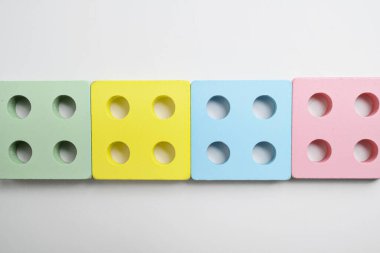 Beyaz arka planda sıralanmış dört delikli renkli ahşap bloklar. Erken eğitim, oyuncaklar, öğrenme ve oyun kavramı