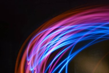 Siyah arkaplana karşı dairesel ve spiral desenli renkli neon ışıklı resmin soyut görüntüsü. Modern ve gelecek tasarım elementi.